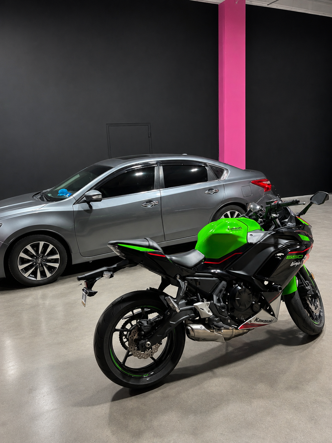 Tinted sedan and motorcycle at Pink Label Wraps garage